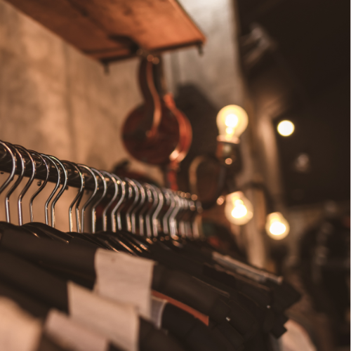 Close-up of clothing rack with shirts on hangers in warm, ambient boutique lighting