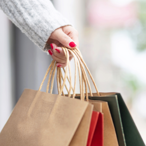 Woman carrying several paper shopping bags to show shopping at various retailers