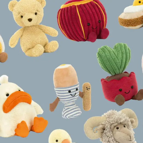 Collection of soft toys from West Coast Kids including a teddy bear, ball, duck, and sheep on a gray background.