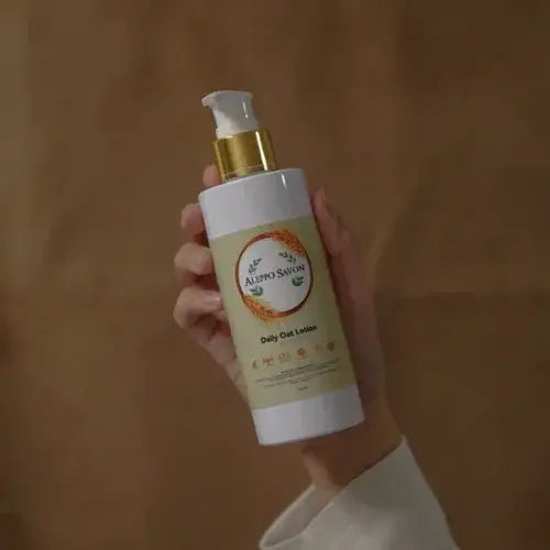 Hand holding a bottle of daily oat lotion against a wooden background.