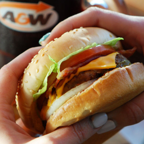 Hand holding a burger with visible A&W logo in the background