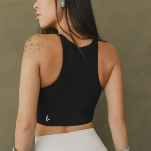 Woman wearing a black sports bra with a visible brand logo on a plain background