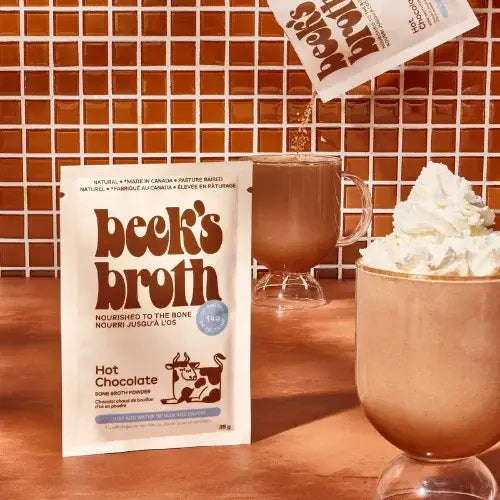 Beck's Broth Hot Chocolate package with a mug of hot chocolate and whipped cream on a wooden surface.