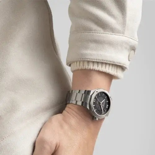 Silver watch on a wrist with a neutral background