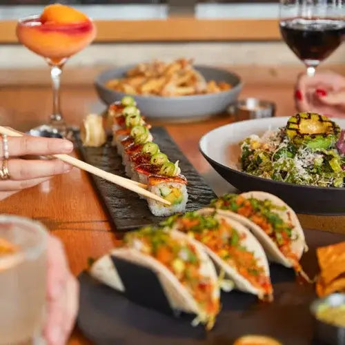 Assorted dishes including sushi, tacos, salad, and cocktails at Canadian-owned Cactus Club Cafe