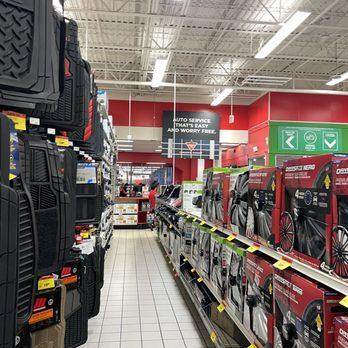 Interior aisle of Canadian Tire showing automotive products like floor mats and car covers, with a sign in the back reading 'Auto service that's easy and worry free'.