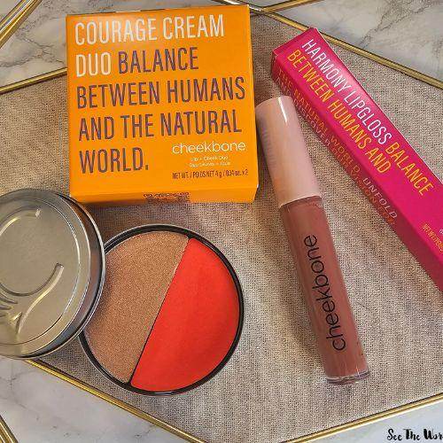 Cheekbone Beauty products including a Courage Cream Duo blush compact with coral and bronze shades, a Harmony lip gloss, and vibrant packaging highlighting the brand’s mission to balance between humans and the natural world.