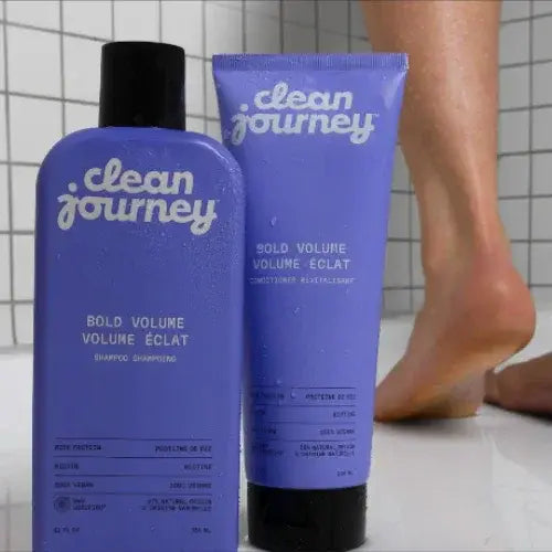 Two bottles of 'clean journey' products on a bathroom floor with tiled walls.