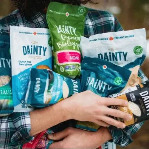 Hand holding multiple packages of Dainty brand products with a blurred background