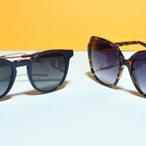 Two pairs of sunglasses on a white surface with a yellow background