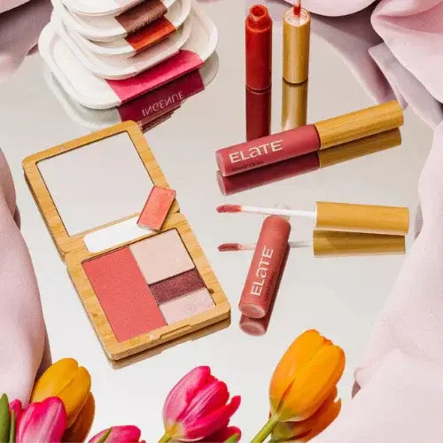 Elate sustainable makeup set with lip gloss, blush palette, and eco-friendly bamboo packaging on mirrored surface with tulips