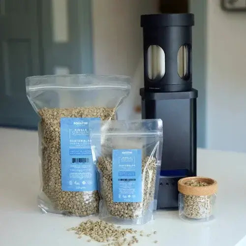 Two packages of coffee beans with a coffee grinder on a kitchen counter.
