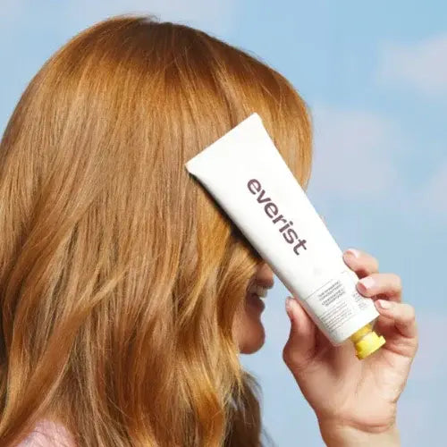 Person holding a white tube with 'everist' text against a sky background