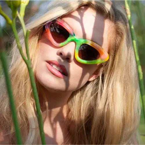 Woman wearing colourful sunglasses with a blurred natural background