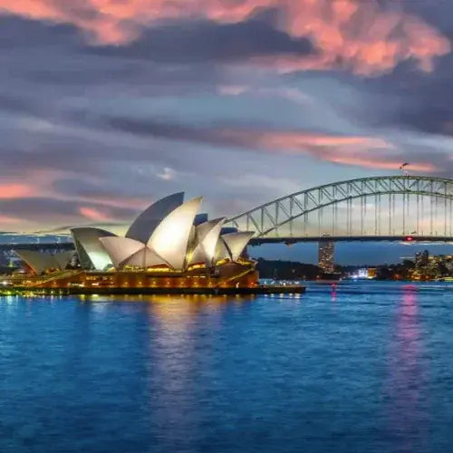 Sydney Opera House and Harbour Bridge at sunset with colorful clouds.