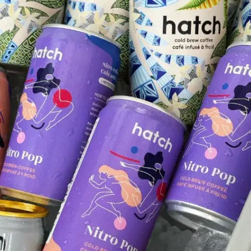 Multiple cans of hatch Nitro Pop cold brew coffee with colorful designs on the labels.