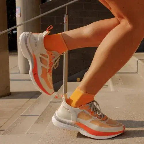 Person wearing orange and white Hettas sneakers on stairs – Stylish, performance-driven footwear by Canadian-owned Hettas