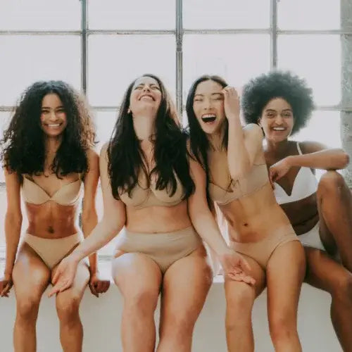 Four women in lingerie sitting together in a well-lit room.