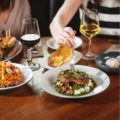 Person dining at a table with various dishes and wine glasses.