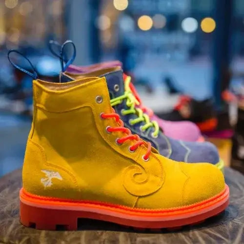 Yellow boot with bright orange sole and neon green laces on a blurred background.
