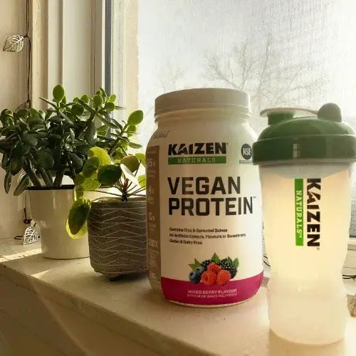 Vegan protein powder container and shaker bottle on a windowsill with plants.