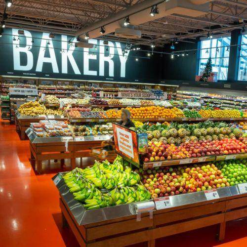 Fresh produce section inside a Loblaws grocery store with bananas, apples, and bakery signage – Canadian-owned supermarket chain