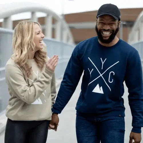 Two people wearing sweatshirts with a logo, standing outdoors.