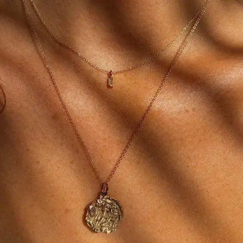 Two gold necklaces on a person's neck with a close-up view of the skin.
