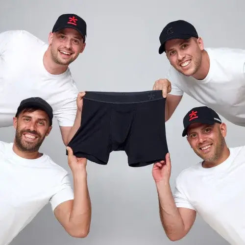 Four men holding a black boxers against a plain background