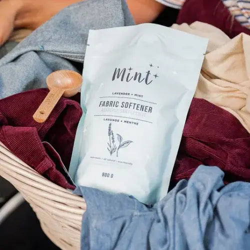 Fabric softener package with a wooden scoop over clothes in a basket