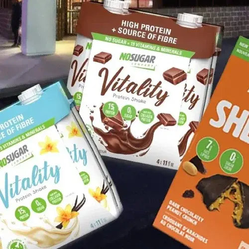 No Sugar Company Vitality protein shake packages in different flavors on a dark surface.