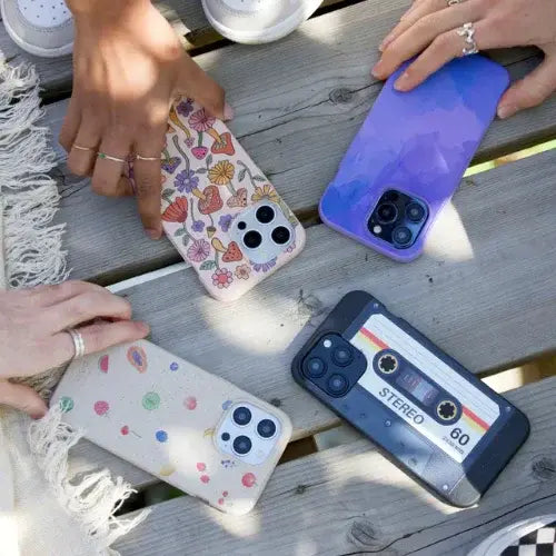 Four phone cases with colorful designs on a wooden table.