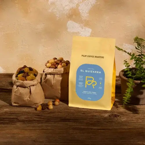 Coffee bag labelled 'El Quizarra' with coffee beans on a wooden surface.
