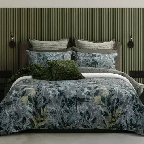 Bed with floral bedding and green pillows against a striped wall.