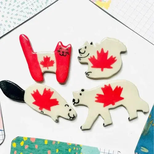 Decorative magnets shaped like bears and a letter 'H' with a red maple leaf design on a colorful background.