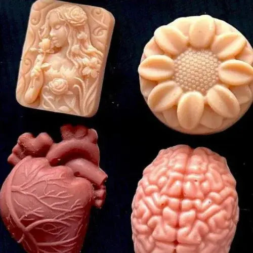 Four soap molds with intricate designs on a dark background