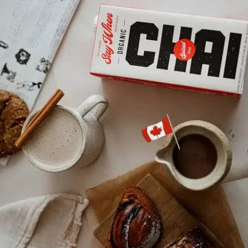Box of organic chai, mug with chai, cookies, and a pastry on a table.
