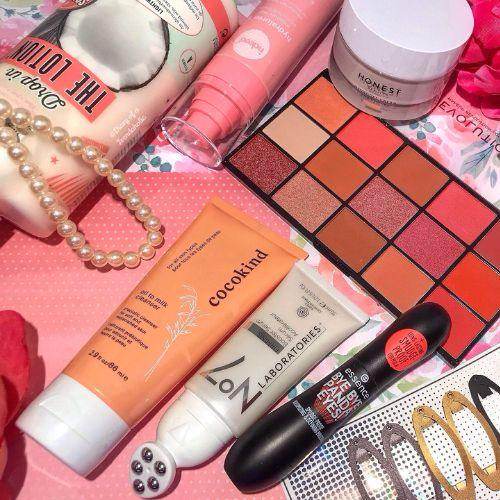 Assorted beauty and skincare products from Shoppers Drug Mart displayed on a pink floral background with a pearl necklace