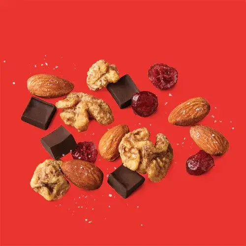 Assorted nuts, chocolate pieces, and cranberries on a red background