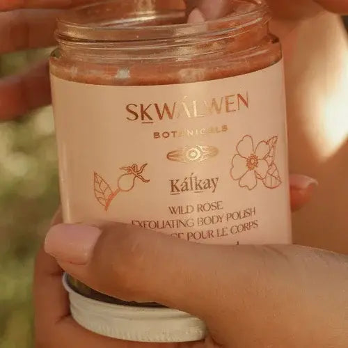 Person holding a jar of Skwalwen Botanicals Kalkay Wild Rose Exfoliating Body Polish.