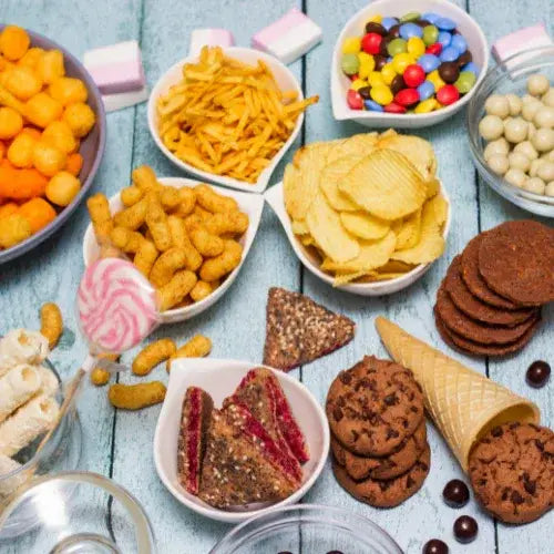 Assorted snacks including chips, cookies, and candies on a wooden surface
