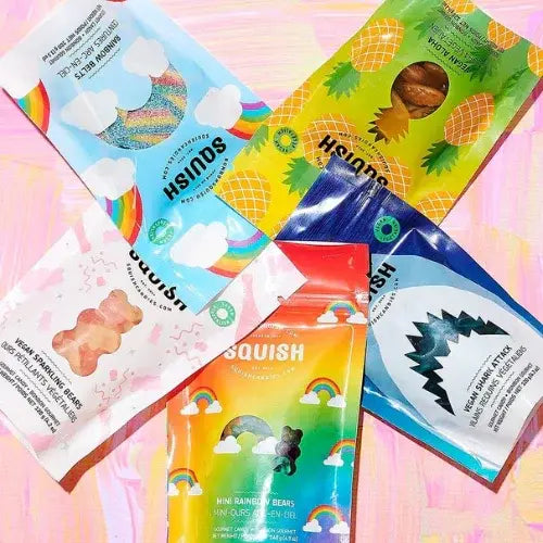 Colourful packages of mini rainbow bears and other items on a pink background