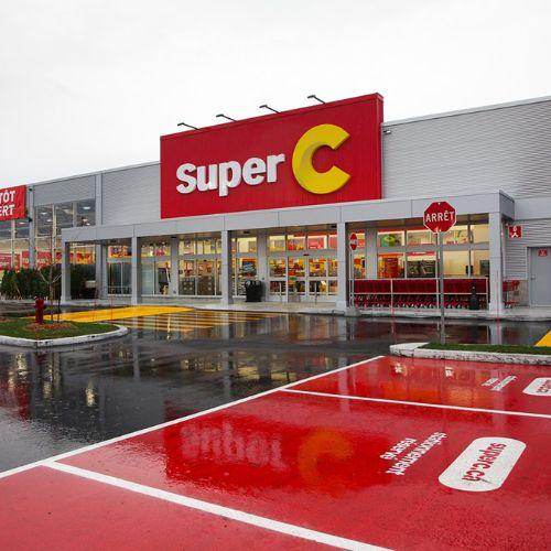 Super C grocery store exterior on a rainy day, with bold red signage and designated parking spots in front of the entrance