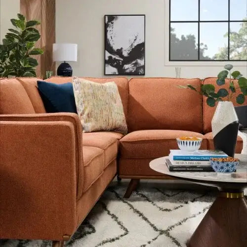 Living room with a brown sectional sofa, decorative pillows, and a coffee table with books and a plant.
