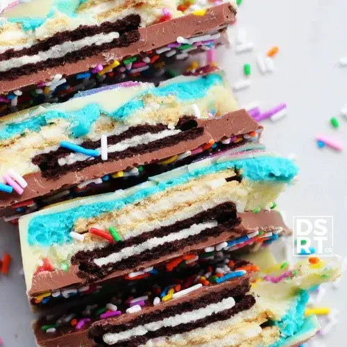 Stack of colourful layered cookies with chocolate, vanilla, and sprinkles on a white background.