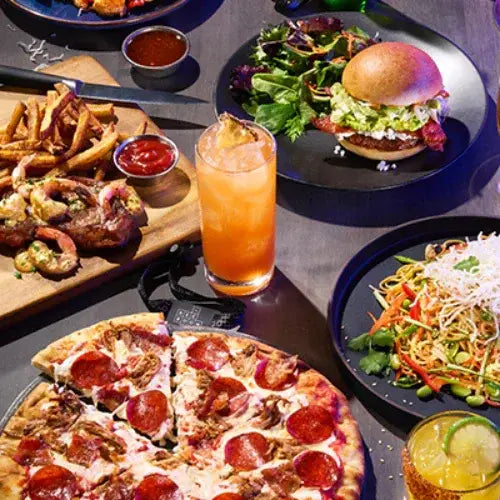 Table with various foods including pizza, burger, salad, and drinks.