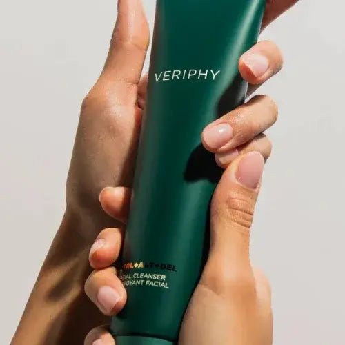 Hands holding Veriphy facial cleanser in a sleek green tube