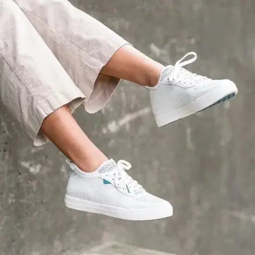 Person wearing white Vessi waterproof sneakers with light grey pants – Canadian-owned brand known for breathable, weatherproof footwear