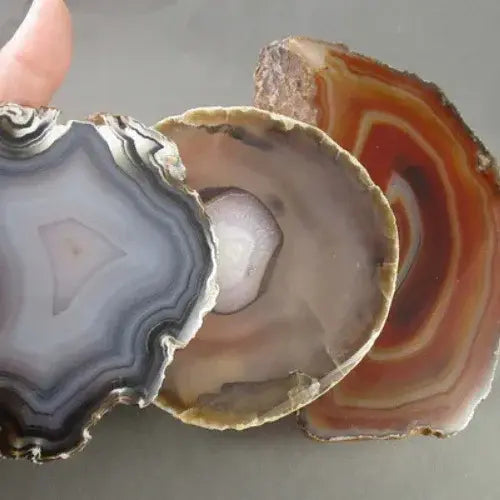 Close-up of three agate slices with different patterns on a gray background