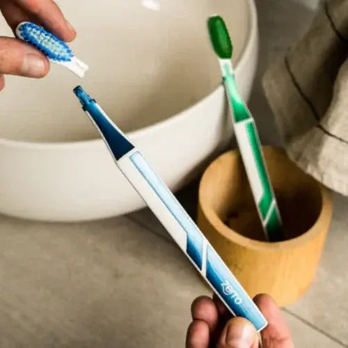 Electric toothbrush held by a hand with two other toothbrushes in the background.